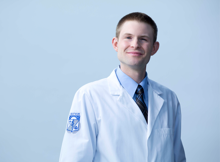 Male student in tie and white coat with LECOM Patch on sleeve at LECOM