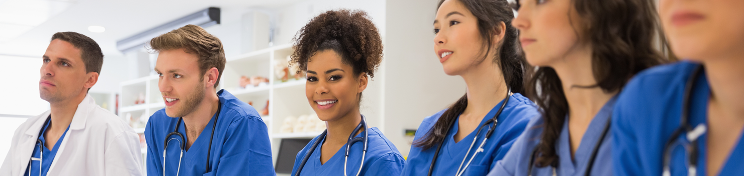 Interracial doctors in blue scrubs arounds table at LECOM