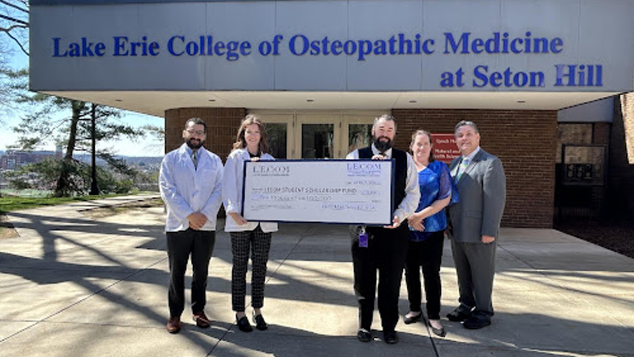 Second-year students Mina Shenouda (far left) and Madison Kober (left) present a donation of five thousand dollars.